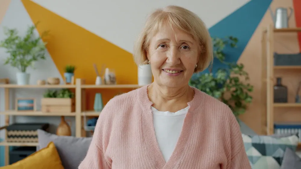 Mujer mayor sonriendo en la sala de su casa