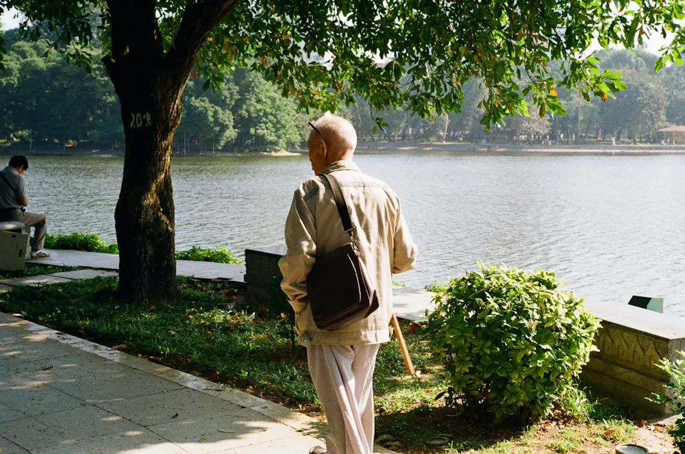 Hombre mayor caminando junto a un lago en un parque