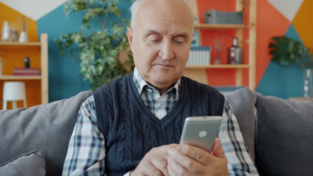 Hombre mayor usando su teléfono en el sofá